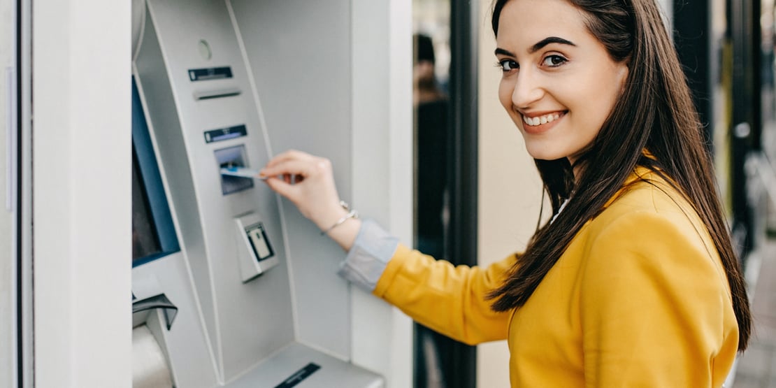 Smiling woman using an ATM machine.